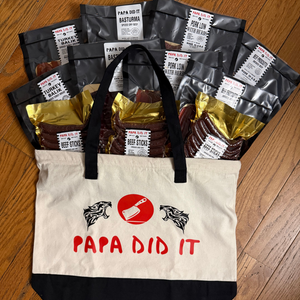 Papa Did It gift tote bag loaded with multiple packs of cured meats and beef sticks on hardwood floor
