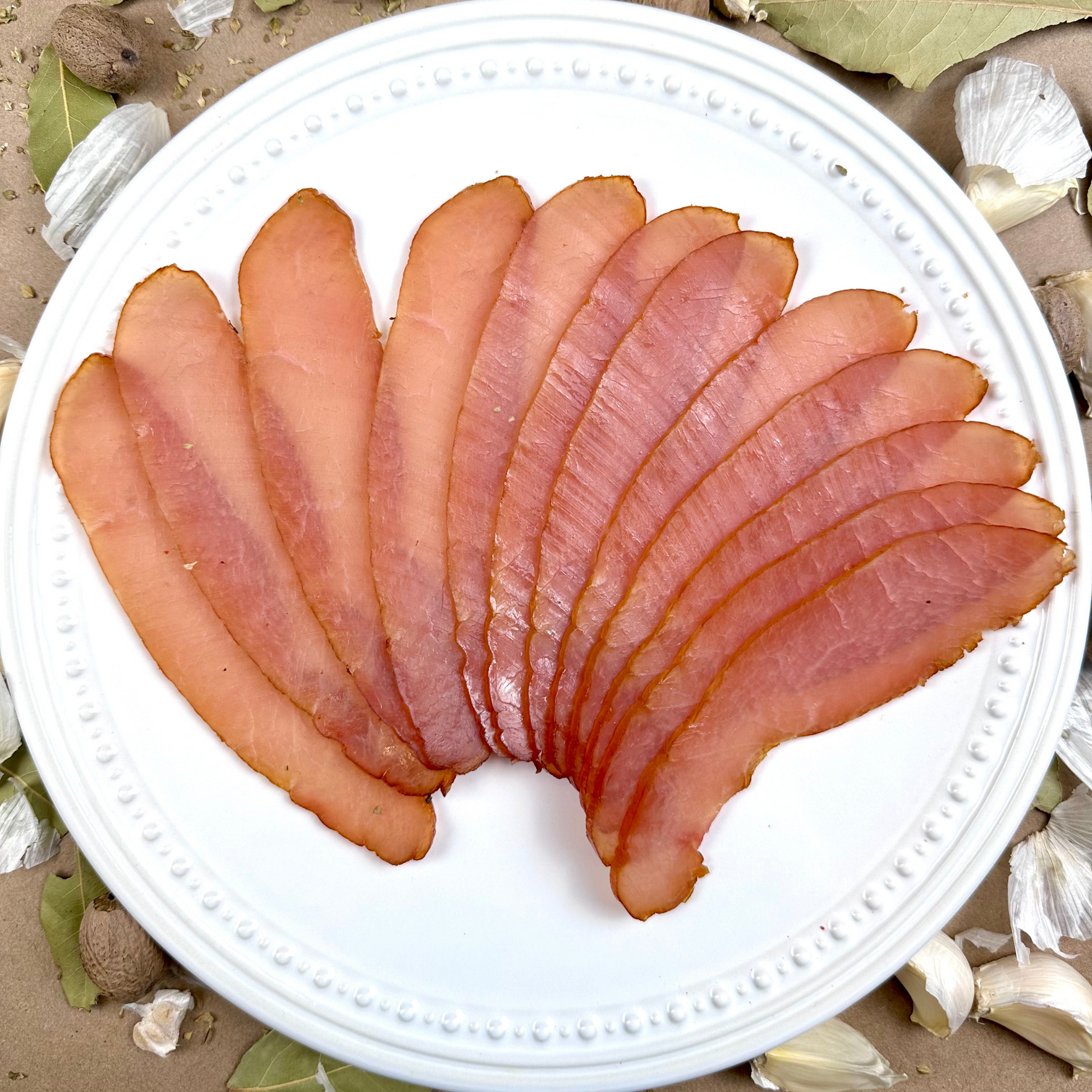Sliced ham on a white plate with a natural background