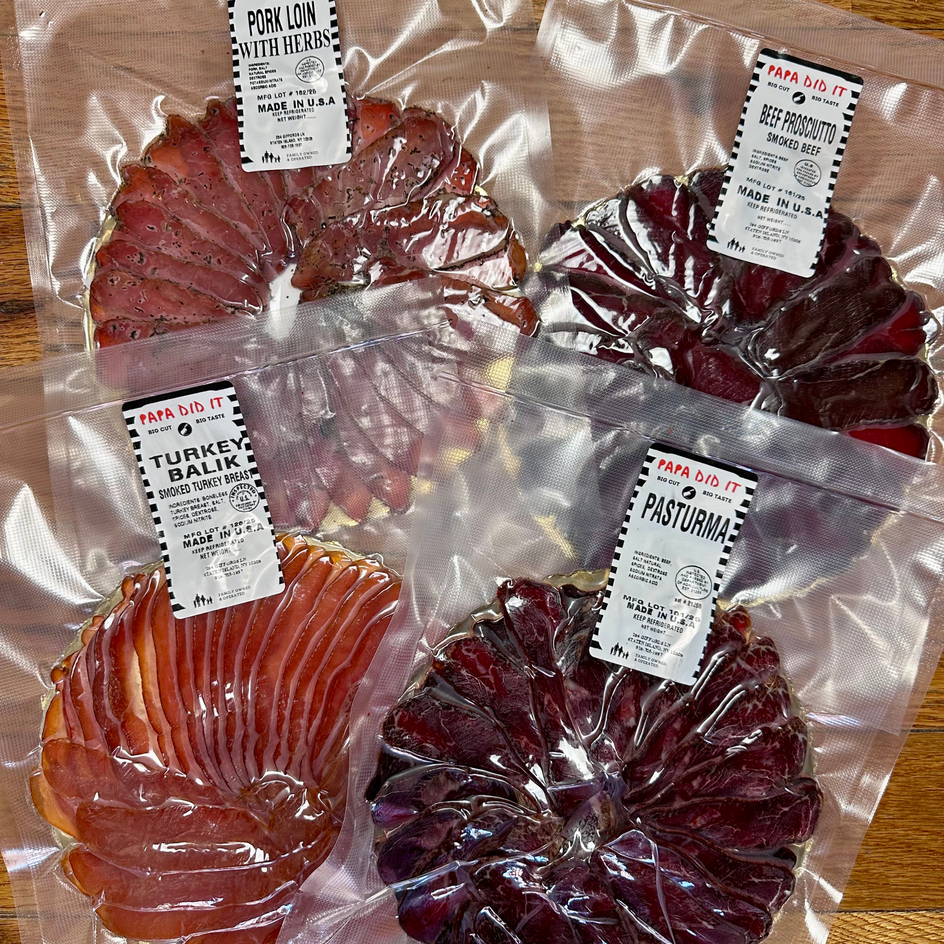 Four vacuum-packed meat products including sliced basturma, turkey balyk, pork loin with herbs, and beef prosciutto.
