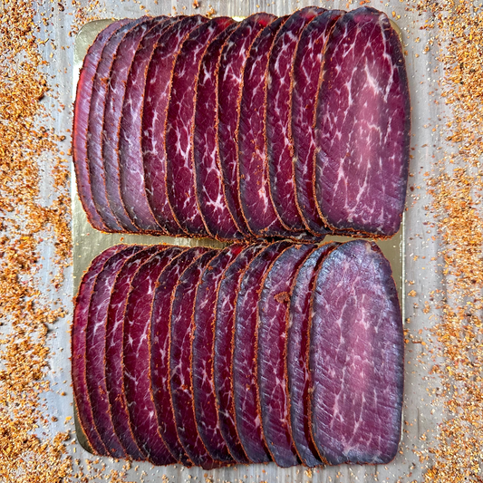 Sliced cured meat on a metal surface with a rustic background