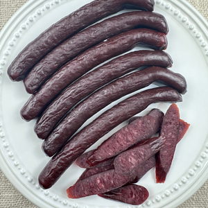 Whole smoked beef sticks arranged neatly on a white plate