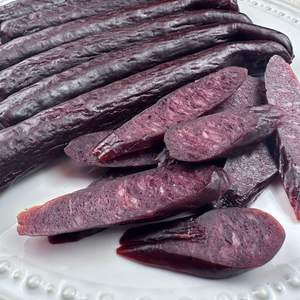 Thick slices of smoked beef sticks laid out beside whole sticks