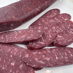 Whole and sliced beef sudjuk served on white plate