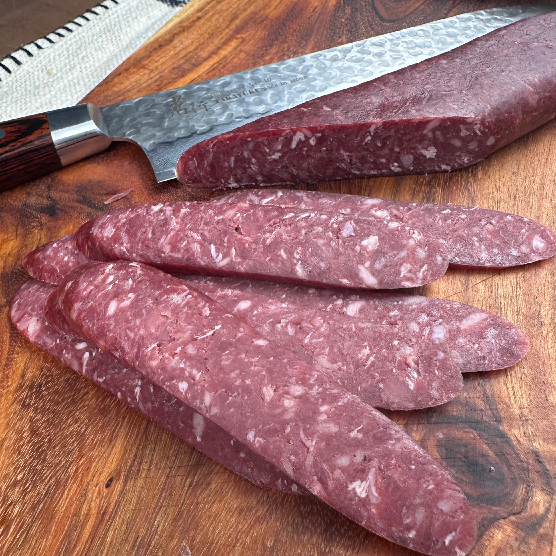 Top-down view of beef sudjuk and slices on a plate