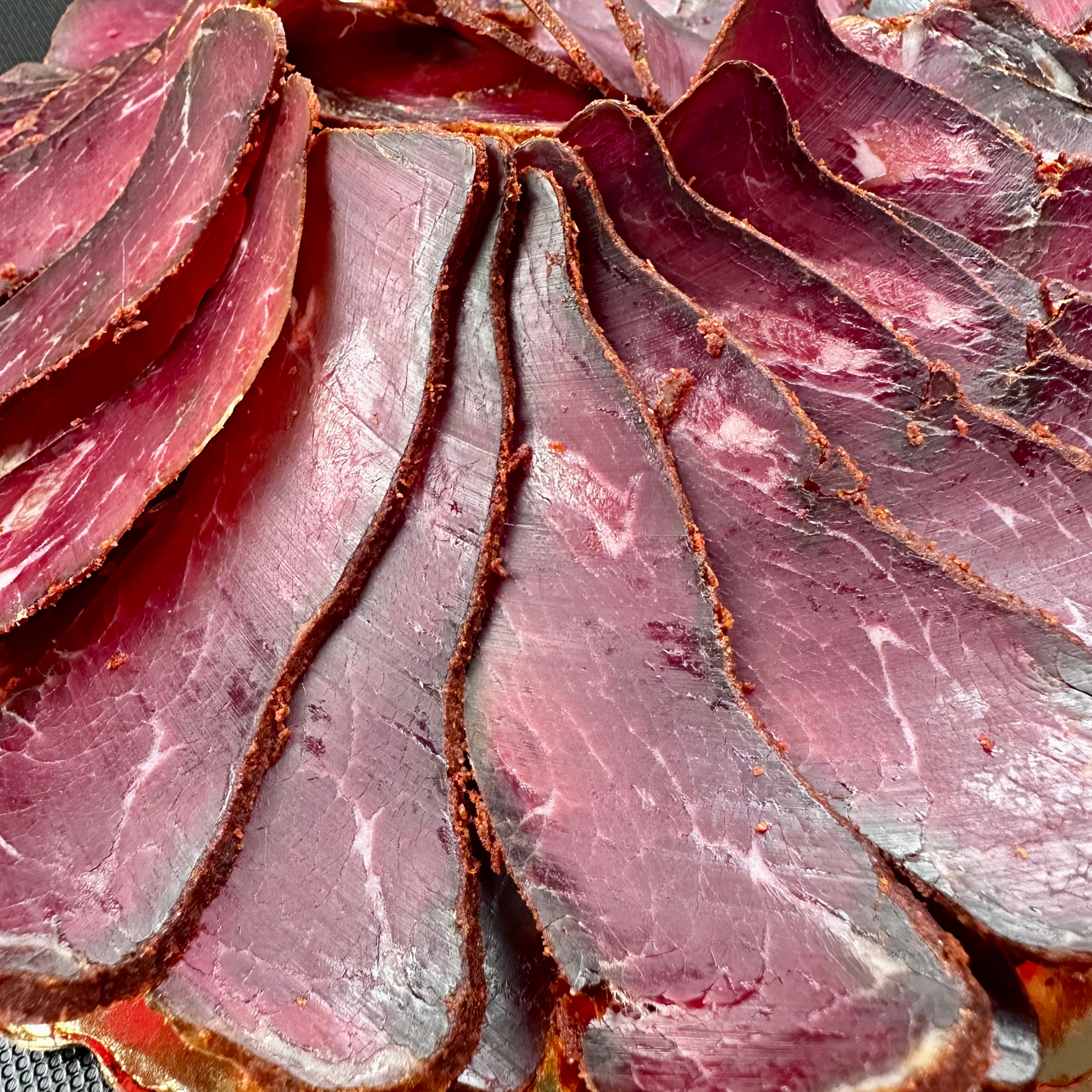 Close-up of sliced cured meat with a marbled texture.