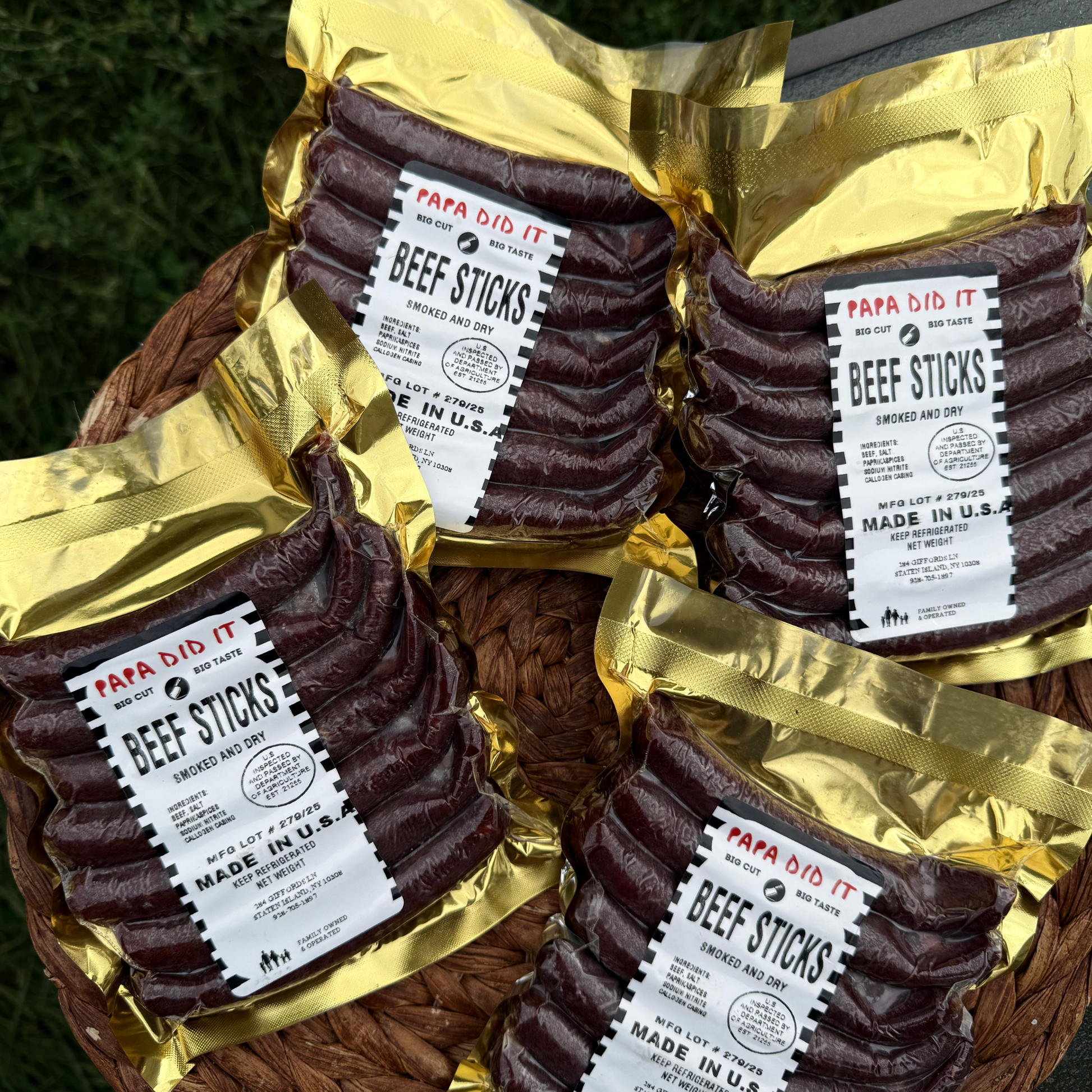 Papa Did It Beef Sticks — four golden vacuum-sealed packs of handcrafted hickory-smoked beef sticks displayed in a rustic basket. Premium dry-cured meat snack made in the USA.