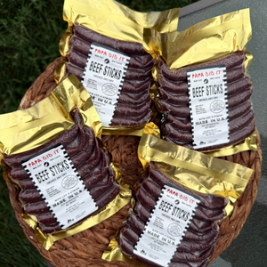 Papa Did It beef sticks in gold vacuum packaging arranged in a basket outdoors