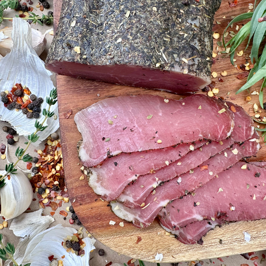 Close-up of smoked pork loin with herbs, sliced on cutting board