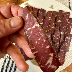 Hand holding a slice of Suho Meso Balkan dry cured beef