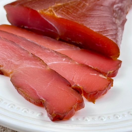 Sliced turkey balyk served on a round white plate
